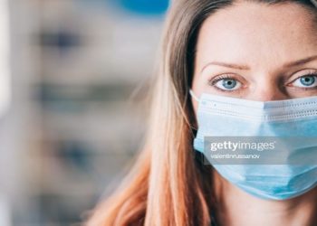 Woman wearing protective face mask in the office for safety and protection during COVID-19