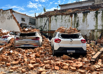 Parte de imóvel desaba sobre estacionamento, danifica três carros e uma motocicleta, mas ninguém fica ferido.